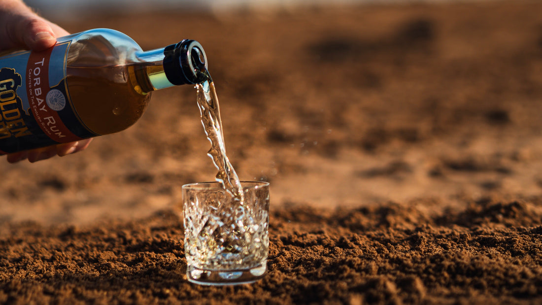 landscape photo of golden spiced rum being poured on the beach